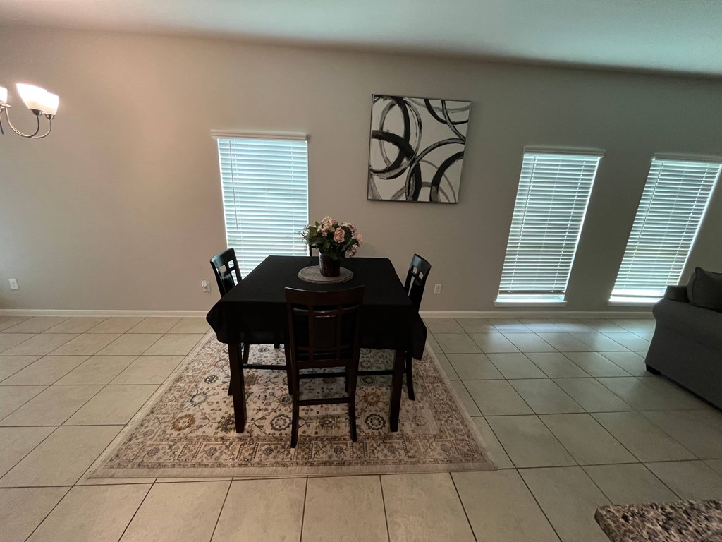 A black dining table with chairs and a vase of flowers in the middle.