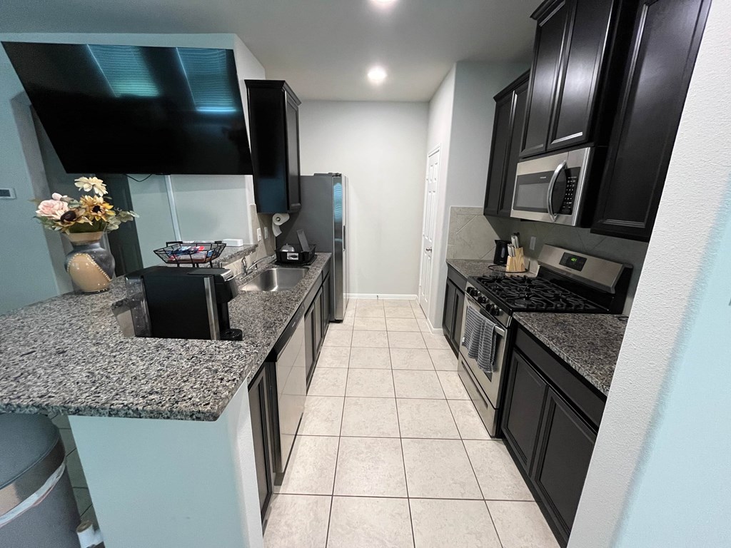 A kitchen with black cabinets and granite countertops.