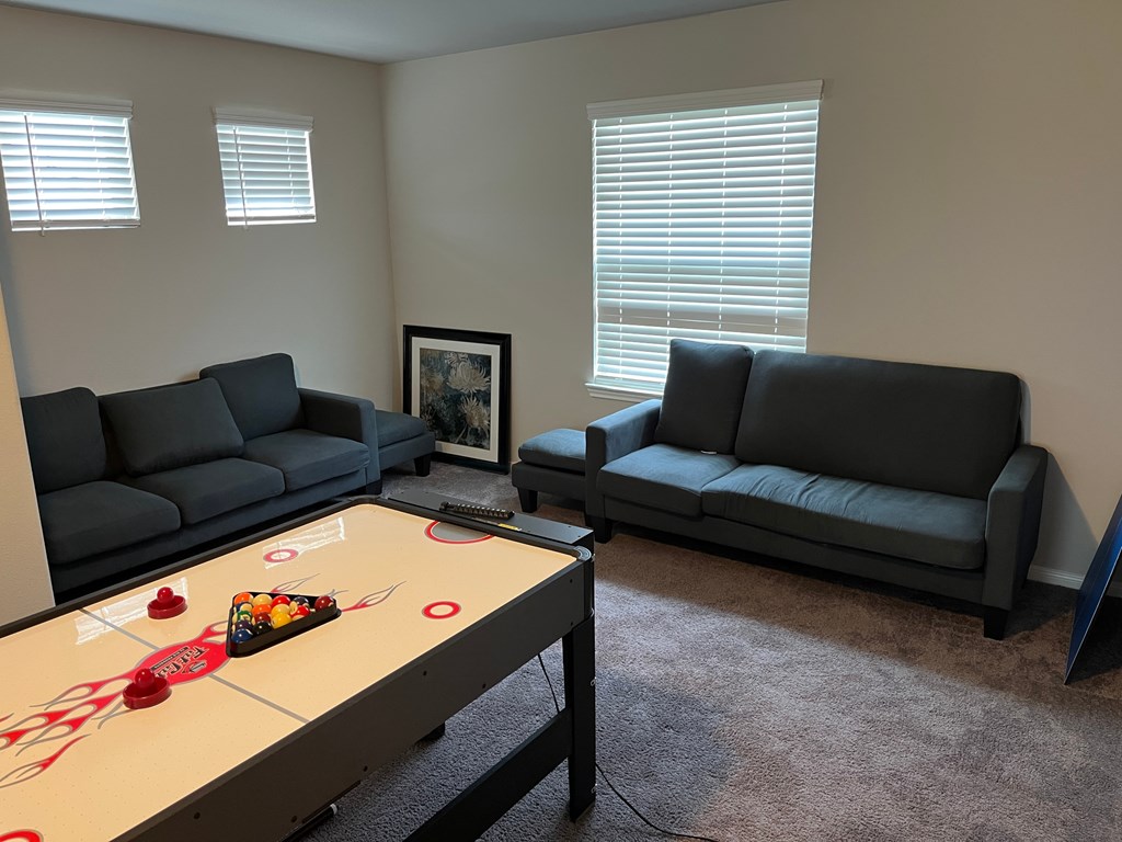 A shiny table with a red and white object on it sits in a room with two grey couches.