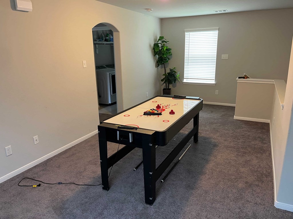 A room with a pool table and a plant.