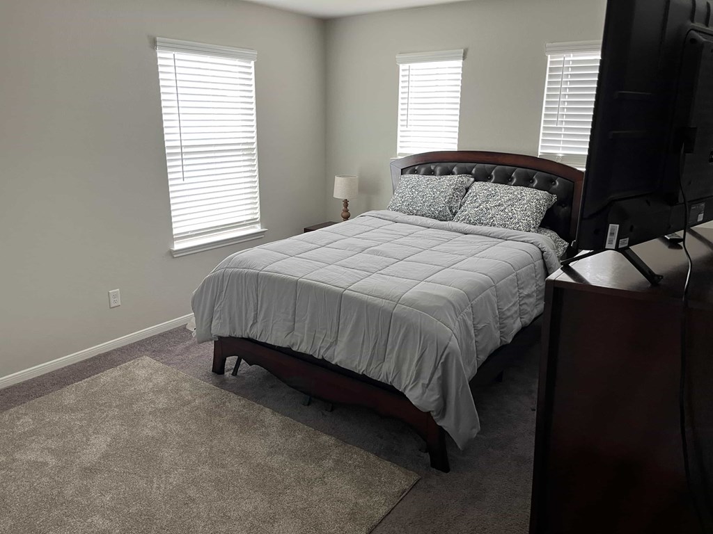 A bedroom with a bed, a lamp, and a TV.