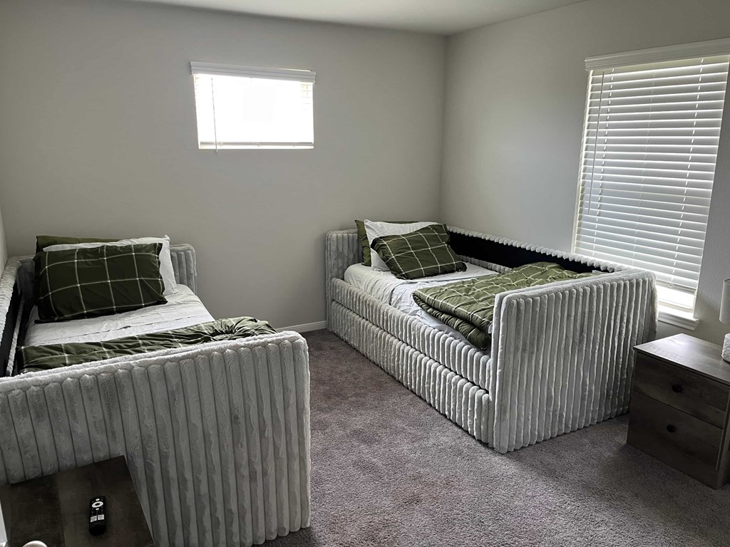 Two twin beds with green pillows in a room.