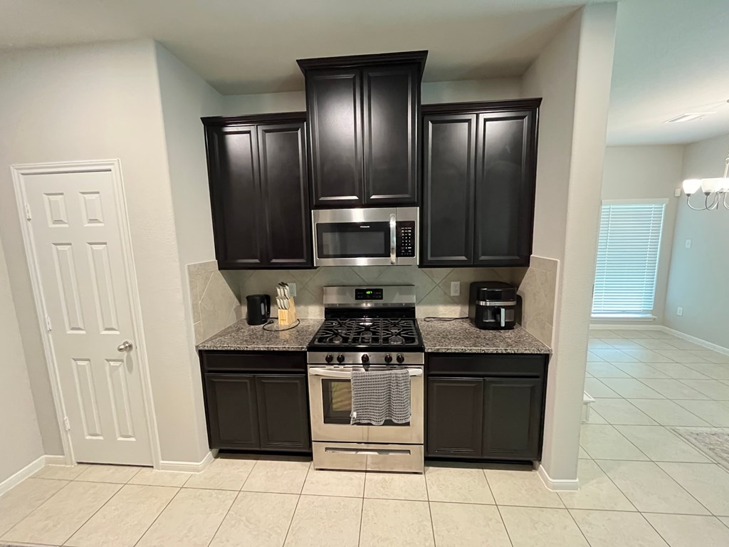 A kitchen with black cabinets and a granite countertop.