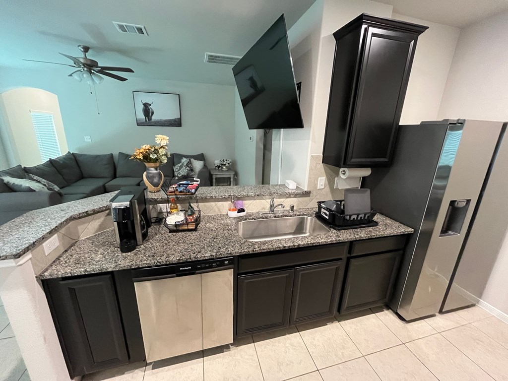 A kitchen with a black fridge and a grey countertop.