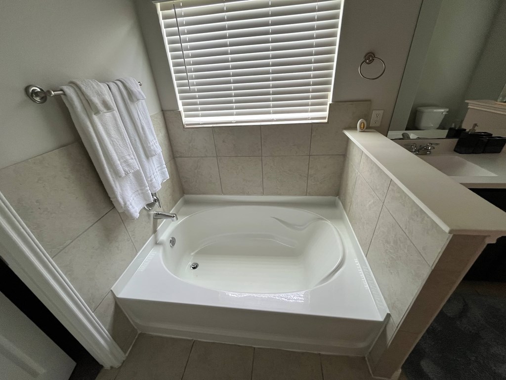 A white bathtub is in a bathroom with a towel hanging on the wall.