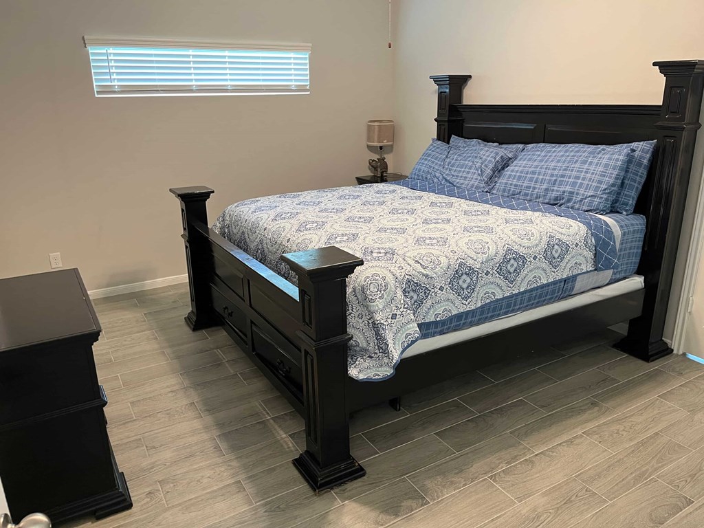 A bed with a black frame and a blue and white patterned comforter.