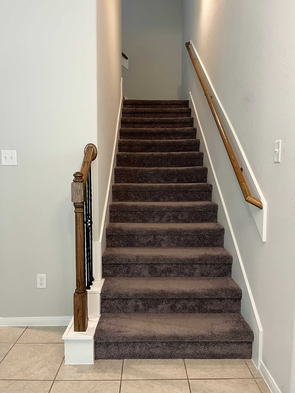 A staircase with a brown carpeted runner and wooden banister.