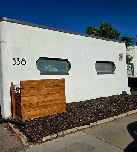 A white building with the number 338 on it has a wooden fence in front.