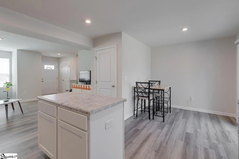 A kitchen with a granite countertop and a dining table with chairs.