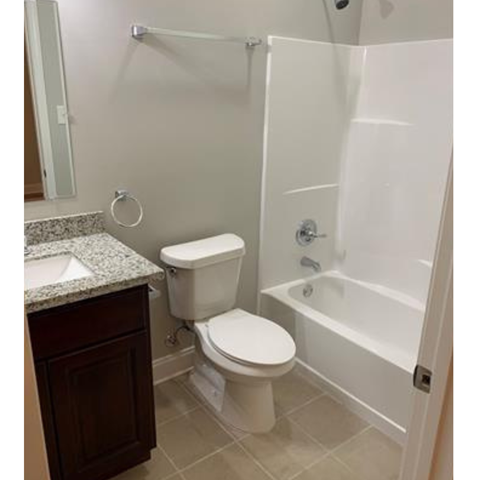 A white toilet sits next to a white bathtub in a bathroom.