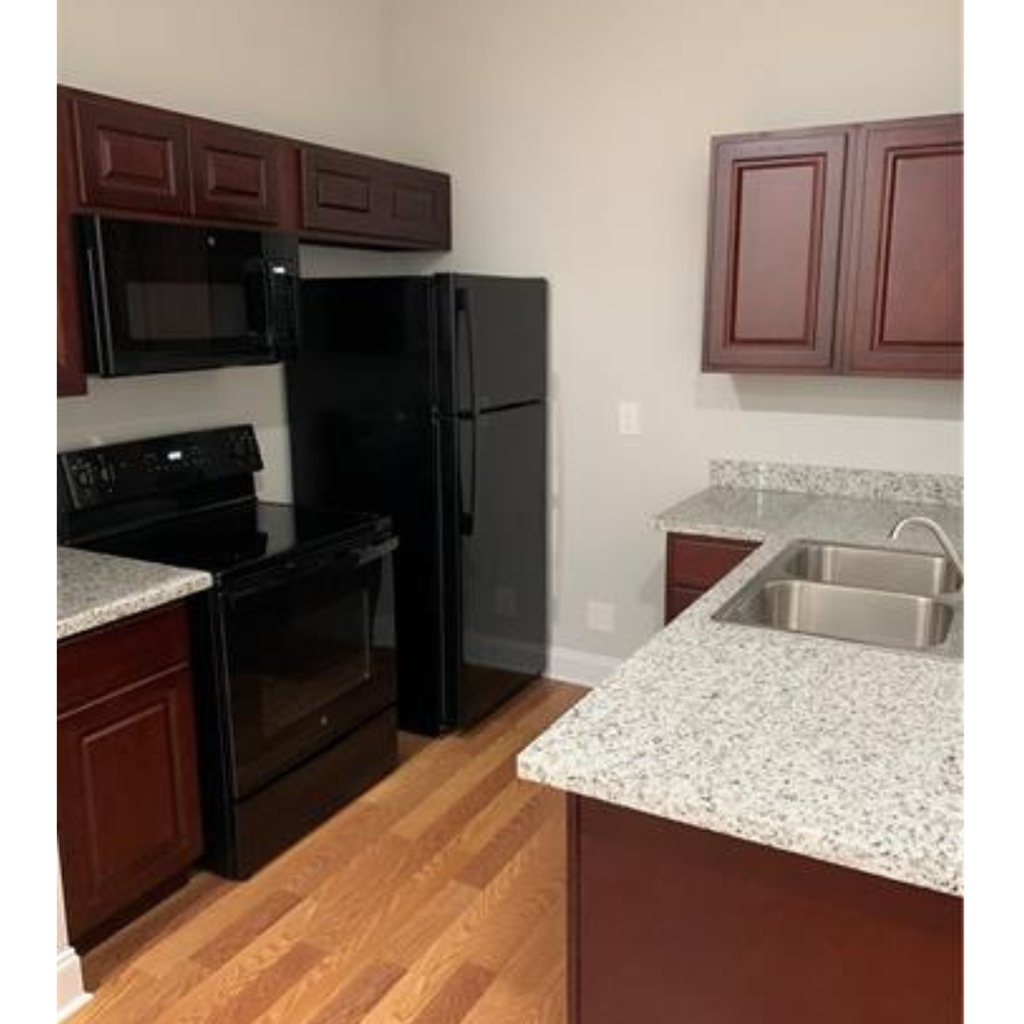 A kitchen with a black refrigerator and wooden cabinets.