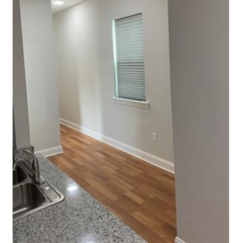 A kitchen with a sink and wooden floors.