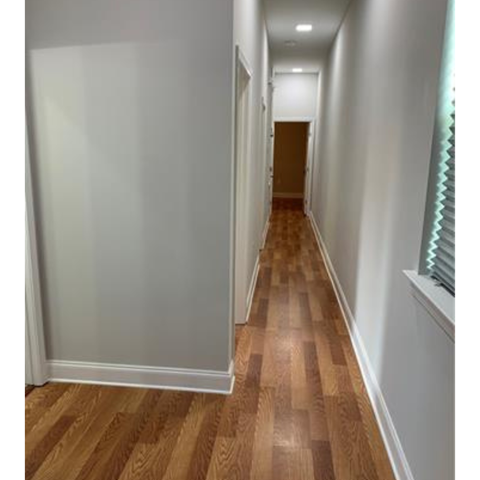 A long hallway with wood flooring and white walls.