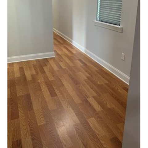 A room with wooden flooring and a window with blinds.