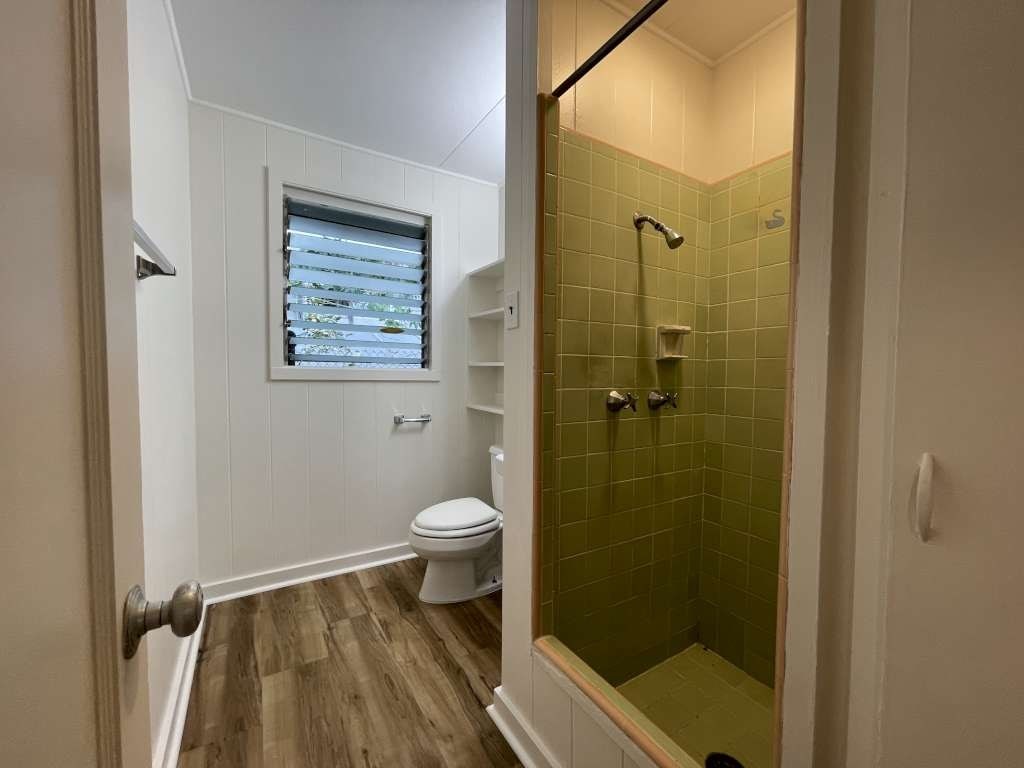 A bathroom with a toilet, a window, and a shower.