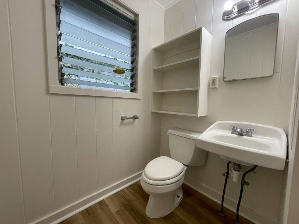 A white toilet sits next to a sink in a small bathroom.