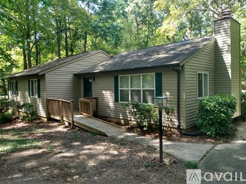 A house with a porch and a chimney is surrounded by trees.