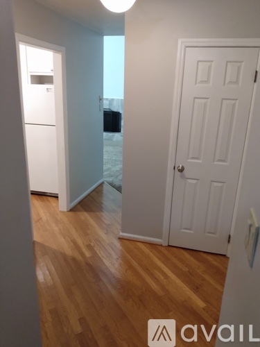 A room with a white door and a wooden floor.