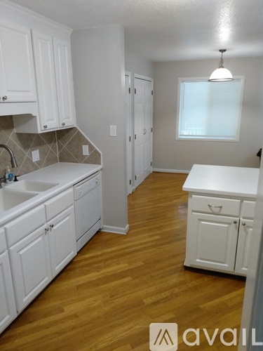 A kitchen with white cabinets and wooden floors.