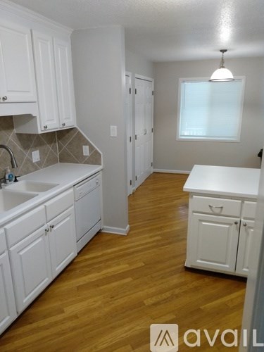 A kitchen with white cabinets and wooden floors.
