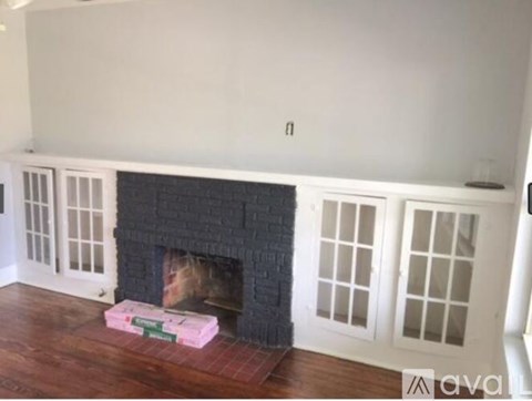 A fireplace with a brick surround and a wooden floor.