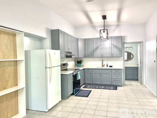 A kitchen with a white refrigerator and grey cabinets.