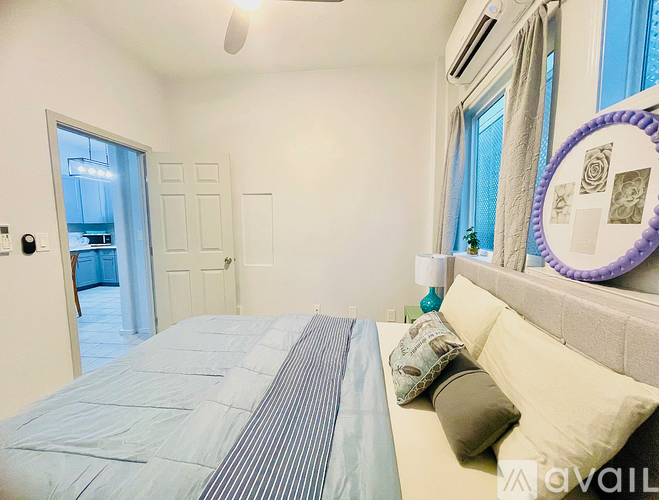 A bedroom with a bed, pillows, and a mirror on the wall.
