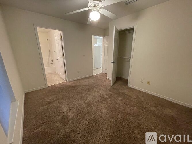 A room with a carpeted floor and a ceiling fan.