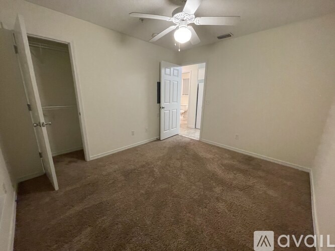 A room with a carpeted floor and a ceiling fan.