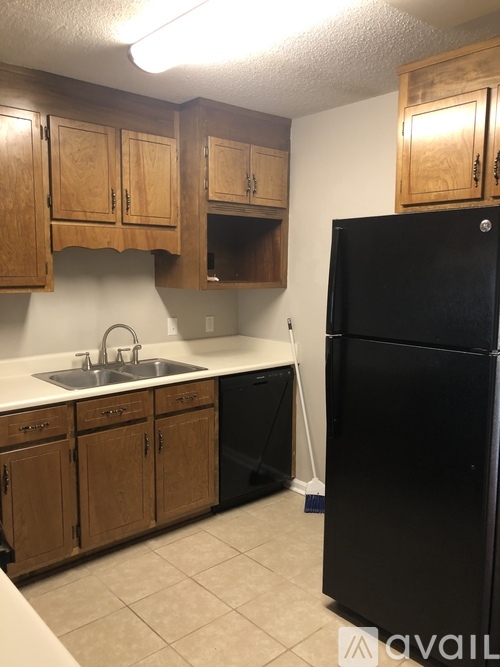 A black refrigerator stands in a kitchen with wooden cabinets.