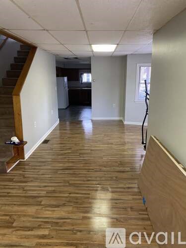 A room with wooden flooring and a staircase on the left side.