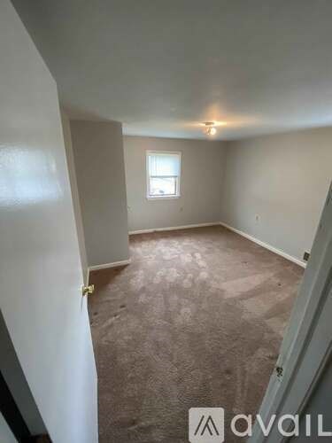 A room with a carpeted floor and a window.