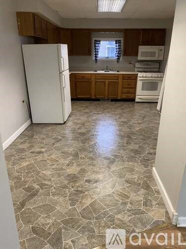 A kitchen with a white refrigerator, wooden cabinets, and a tiled floor.