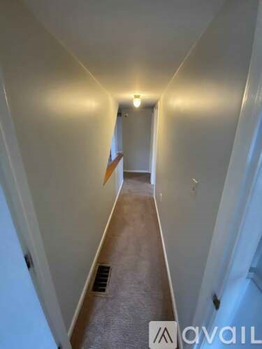 A hallway with a carpeted floor and white walls.