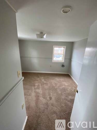 A room with a window and carpeted floor.