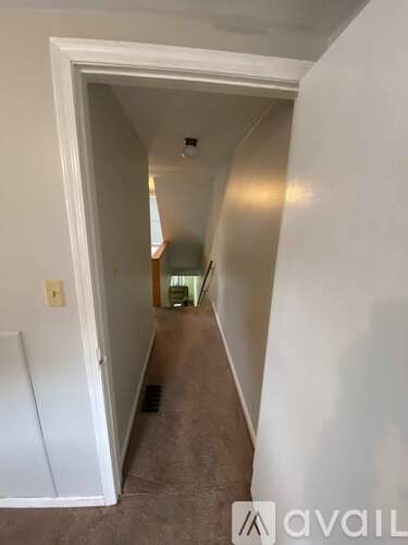 A hallway with a white door and carpeted floor.