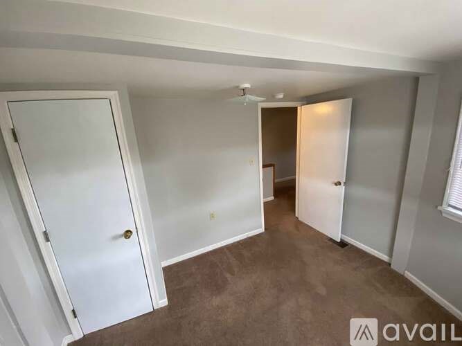 A room with a white door and a brown carpet.