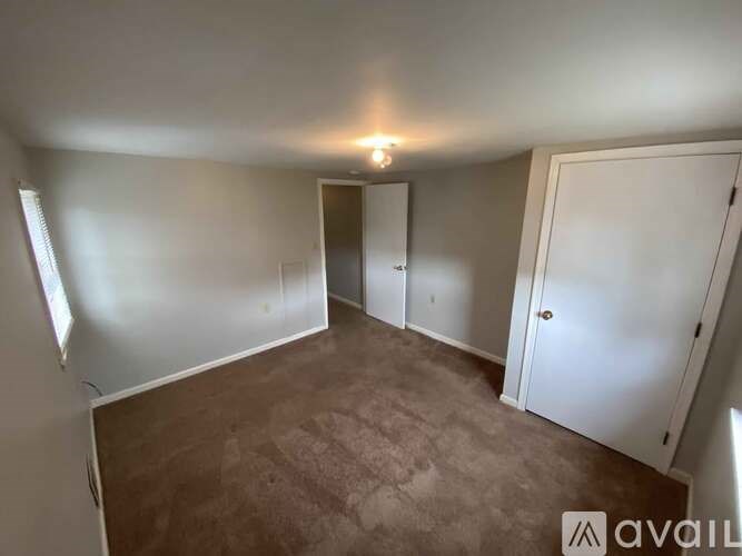 A room with a carpeted floor and two doors.