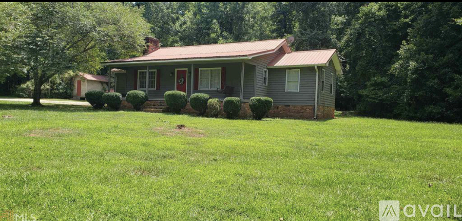 A house with a red door and a green lawn in front.