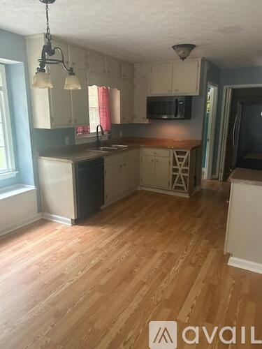 A kitchen with wooden floors and white cabinets.
