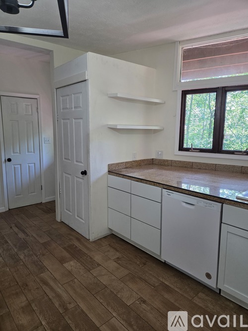 A kitchen with white cabinets and a brown floor.