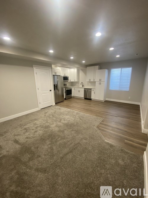 A well-lit, empty room with a kitchenette and a window.