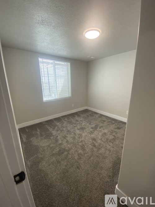 A room with a carpeted floor and a window with blinds.