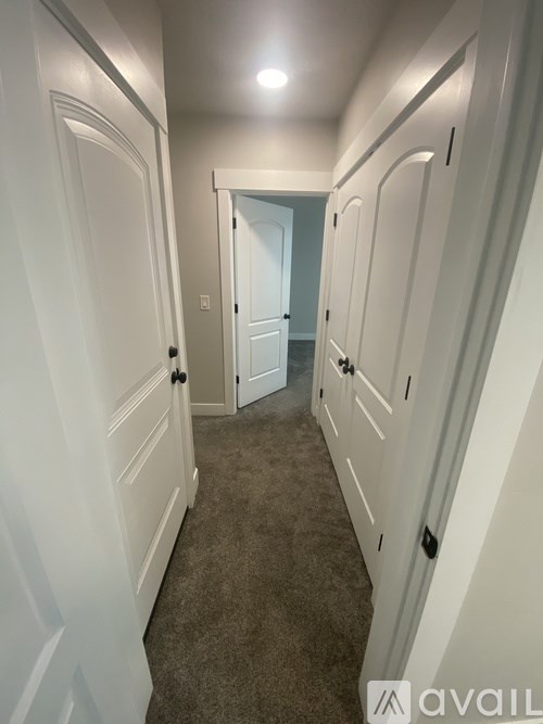 A hallway with white doors and carpeted floor.