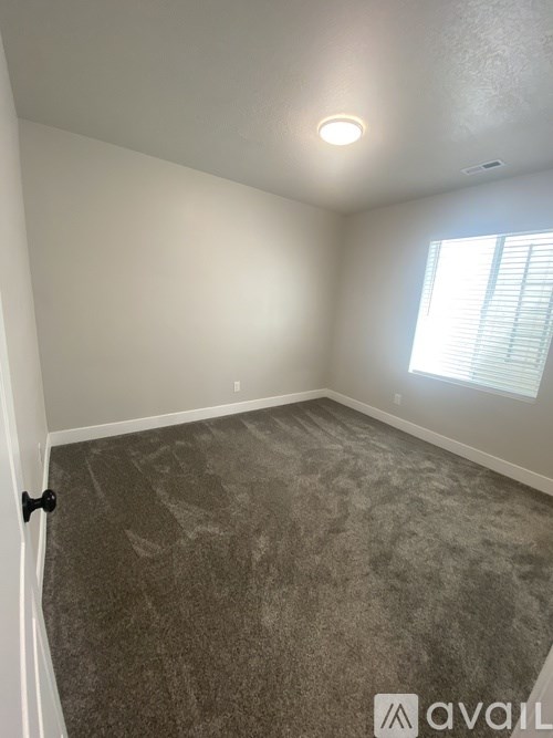A room with a carpeted floor and a window with blinds.