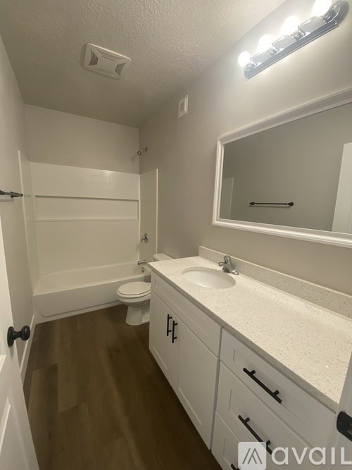 A bathroom with a toilet, sink, and mirror.