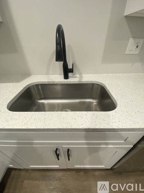 A kitchen sink with a black faucet and a white countertop.