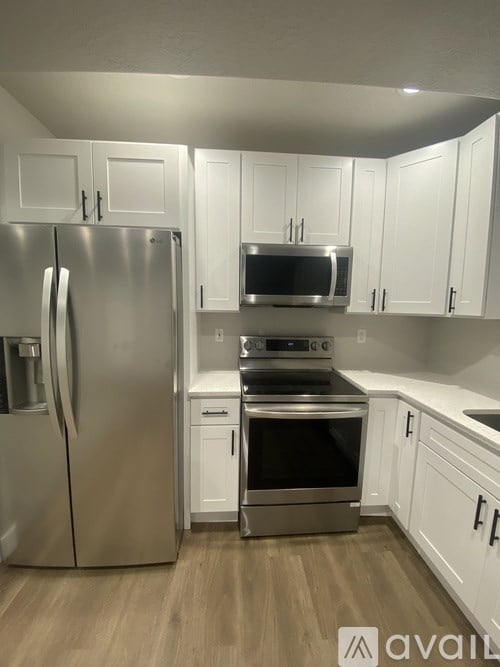 A kitchen with a stainless steel refrigerator and white cabinets.