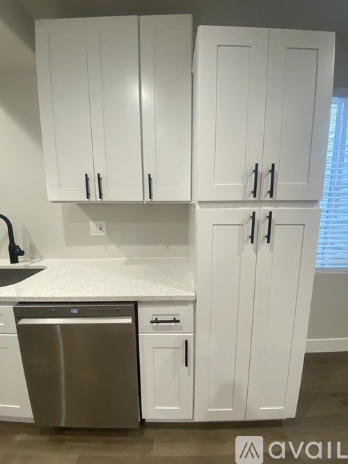 A kitchen with white cabinets and a stainless steel dishwasher.