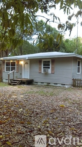 A house with a porch and a tree in front of it.